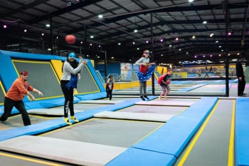 Children in superhero costumes on trampolines